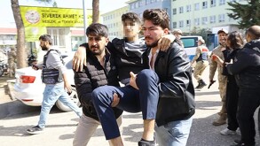 Alumno de una escuela en Turquía con la cara censurada, siendo cargado por dos hombres con militares, policías y estudiantes alrededor