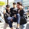 Alumno de una escuela en Turquía con la cara censurada, siendo cargado por dos hombres con militares, policías y estudiantes alrededor