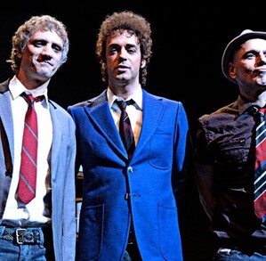 Integrantes de la banda de rock Soda Stereo, Charly Alberti, Gustavo Cerati y Zeta Bosio parados delante de un escenario