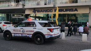 Patrulla de policía afuera de una sucursal de banco Inbursa en Puebla.