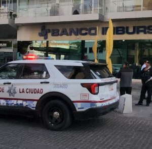 Patrulla de policía afuera de una sucursal de banco Inbursa en Puebla.