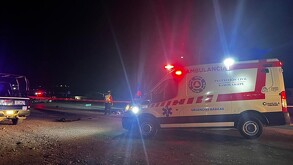 Se observa una patrulla, una cinta roja de precaución y unas motos en el suelo; es de noche.