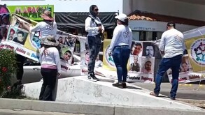 Miembros de colectivo de búsqueda de Jalisco colocando lonas con fotos de desaparecidos sobre el camellón de una calle en Sinaloa