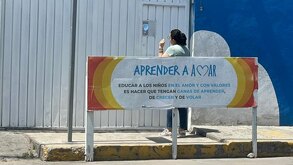 Mujer parada afuera de la puerta de una escuela en Puebla.