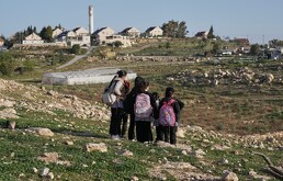 Estudiantes palestinos caminan a la escuela por una ruta alternativa cerca separa su aldea del asentamiento israelí de Carmel, cerca de la aldea de Umm al-Khair