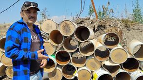 Hombre parado junto a una pila de contenedores en un espacio abierto.