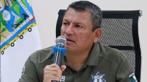 Hombre con uniforme policiaco habla ante un micrófono.