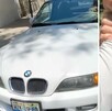 A la izquierda la vista del frente de un auto BMW color blanco. A la derecha un hombre sujetando por el brazo a otra persona
