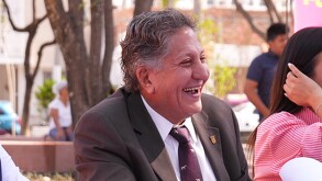 Presidente municipal de Zapopan, Juan José Frangie sonriendo mientras está sentado al lado de una mujer durante un evento público