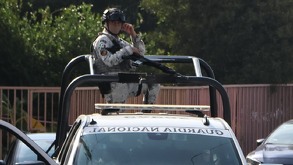 Hombre con uniforme de la Guardia Nacional parado en la batea una patrulla.