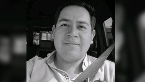 Juan Pérez Romero adentro de su automóvil con un fondo blanco y negro por el luto del asesinato