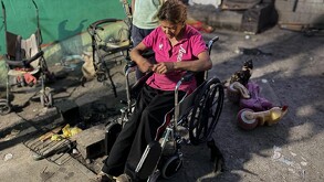 Se observa a una mujer de la tercera edad en una silla de ruedas; viste una blusa color rosa.