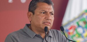 Hombre de avanzada edad y rostro reacio hablando ante un micrófono.