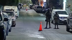 Militares de la Secretaría de la Defensa Nacional resguardando una calle con autos estacionados y conos naranjas