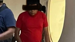 un hombre con una playera roja y pantalones café detenido