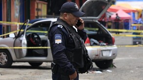 Policía hablando por teléfono junto a un vehículo asegurado.