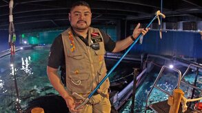 Familia de visitantes del Acuario Michin en una foto con el nombre de la empresa de fondo