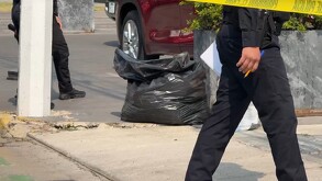 Bolsa de basura negra donde fue encontrado un cráneo con policías de Zapopan alrededor y una cinta policiaca acordonando el área con autos alrededor