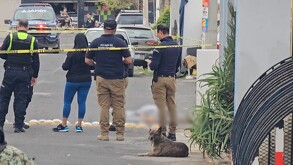 Vista de una calle de Tonalá con policías municipales al fondo acordonado el exterior de una casa con autos y viviendas alrededor