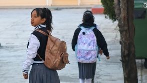 dos niñas con uniforme escolar caminan hacia su escuela