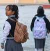 dos niñas con uniforme escolar caminan hacia su escuela