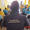 Vista de espaldas de un agente de la Policía de Investigación de Jalisco detrás de un grupo de internos sentados dentro de un centro de rehabilitación