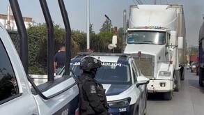 Patrulla y policías junto a un tráiler estacionado en la carretera.