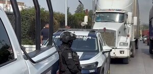 Patrulla y policías junto a un tráiler estacionado en la carretera.