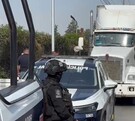 Patrulla y policías junto a un tráiler estacionado en la carretera.