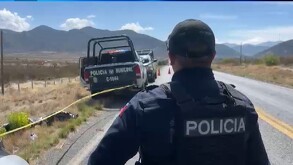 Se observa a un hombre policía de espaldas y una cinta amarilla de precaución.