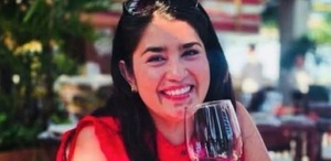 Mujer sonriendo con una copa de vino en la mano.