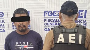 Hombre adulto con los ojos cubiertos junto a un policía con las siglas 
