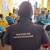 Vista de espaldas de un agente de la Policía de Investigación de Jalisco detrás de un grupo de internos sentados dentro de un centro de rehabilitación