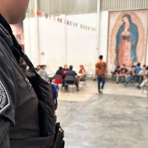 Vista parcial de un oficial del Grupo de Operaciones Fénix de Tlaquepaque con un grupo de menores y un cuadro de la Virgen de Guadalupe desenfocados en el fondo