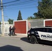 Se observa una patrulla estacionada y unos policías parados en la vía pública.