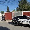 Se observa una patrulla estacionada y unos policías parados en la vía pública.