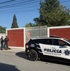 Se observa una patrulla estacionada y unos policías parados en la vía pública.
