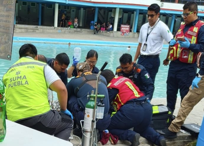 Paramédicos reunidos junto a una persona en una alberca.