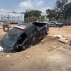 Patrulla de la Policía de Guadalajara con la parte delantera hundida dentro de un socavón en un terreno baldío con basura y escombros alrededor