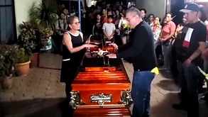 Personas en un funeral con el féretro al centro.