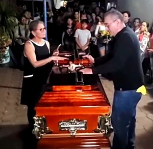 Personas en un funeral con el féretro al centro.