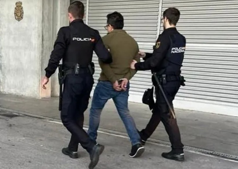 Alejandro Reynoso Jiménez visto de espaldas mientras es detenido por dos policías de España en calles de Madrid