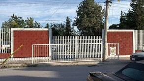 Se observa una fachada de un lugar de ladrillo color guindo.