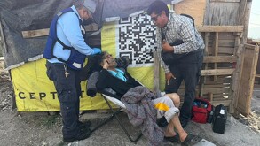 Se observa a un adulto mayor muy delgado, está sentado, hay dos personas a sus costados.