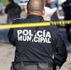 Oficial de la Policía Municipal en Jalisco con una cinta policiaca amarilla acordonando una zona con policías y patrullas desenfocadas en el fondo