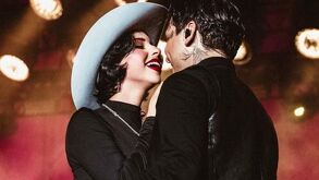 Nodal y Ángela Aguilar sonriendo en escenario.