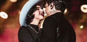 Nodal y Ángela Aguilar sonriendo en escenario.