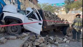 Camioneta blanca cargada con bloques de concreto estrellada contra una barda y acordonada por cinta policiaca con un bombero de Tlaquepaque detrás