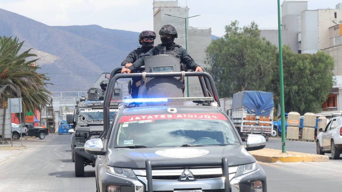 Policías viajando arriba de una bate de una patrulla oficial.