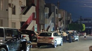 Patrulla de la Policía de Zapopan estacionada fuera de edificios de departamentos con autos estacionados, personas y oficiales alrededor